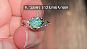 silver cremation ring leaf motif being held between fingers.