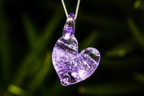 cremation heart pendant with cremation ash hanging in purple