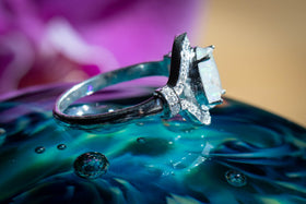 Side view of the Oval Eye Ring with white opal sitting atop a glass surface. Sterling Silver Ring, Sterling Silver Ring with Zircon, Sterling Silver Ring for Ash, Silver Ring for Cremains, Jewelry for Cremation Ash, Remembrance Jewelry, Silver Remembrance Jewelry