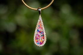 Photo depicts Bedazzled Drop Pendant on chain facing the viewer. The sterling silver pendant is bedazzled with cubic zirconia and filled with a rainbow selection of crushed opal. Sterling Silver Necklace for Cremation Ash, Sterling Silver Necklace for Ash, Sterling Silver Necklace with Zircon, Necklace for Remembrance