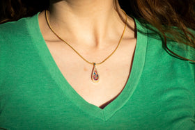 Photo depicts a model wearing the Bedazzled Drop Pendant on chain. The sterling silver pendant is bedazzled with cubic zirconia and filled with a rainbow selection of crushed opal. Sterling Silver Necklace for Cremation Ash, Sterling Silver Necklace for Ash, Sterling Silver Necklace with Zircon, Necklace for Remembrance
