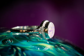 Side view of Braided Oval OPal Cremation Ring, in icy purple and white, sitting atop a glass surface. Sterling Silver Ring for Ash, Sterling Silver Jewelry for Ash, Remembrance Ring, Remembrance Jewelry, Ring for Cremation Ash