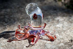 glass octopus figurine with cremation ash on rock