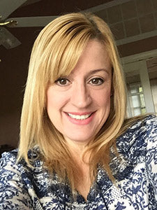 Smiling blonde woman in a blue patterned blouse indoors for a Spirit Pieces Blog interview.