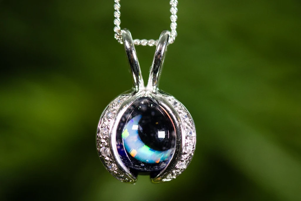 Pet cremation ashes keepsake pendant with a luminous round centerpiece set in a silver crescent frame on a delicate chain