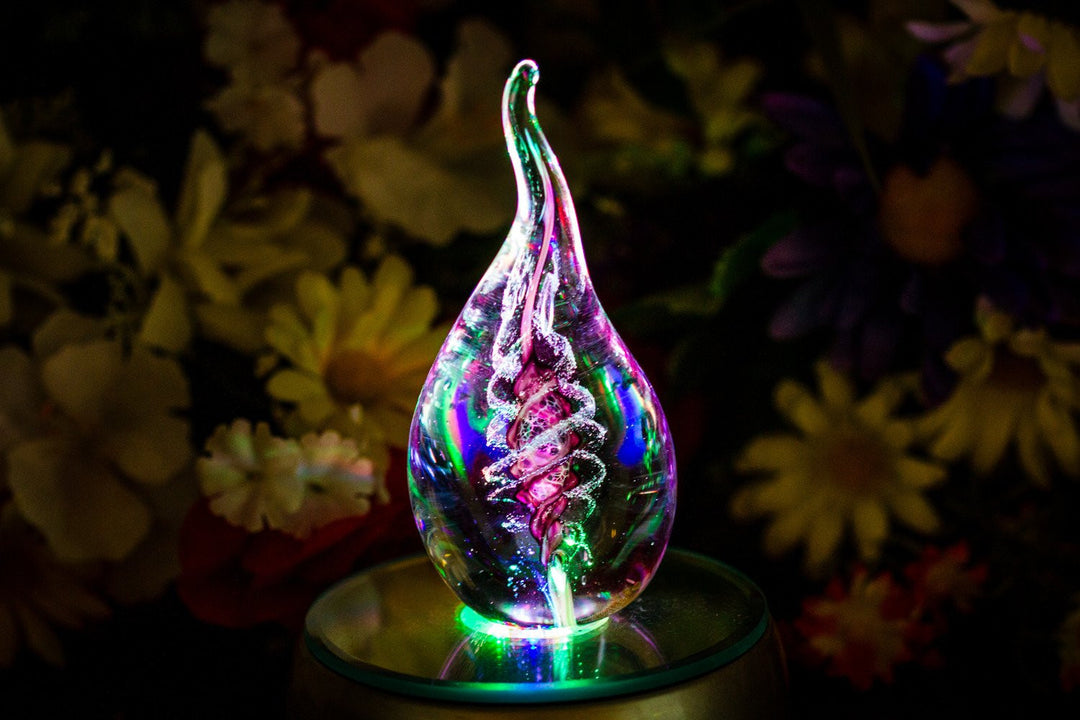 Vibrant glass memorial flame sculpture with colorful swirls and base illumination.
