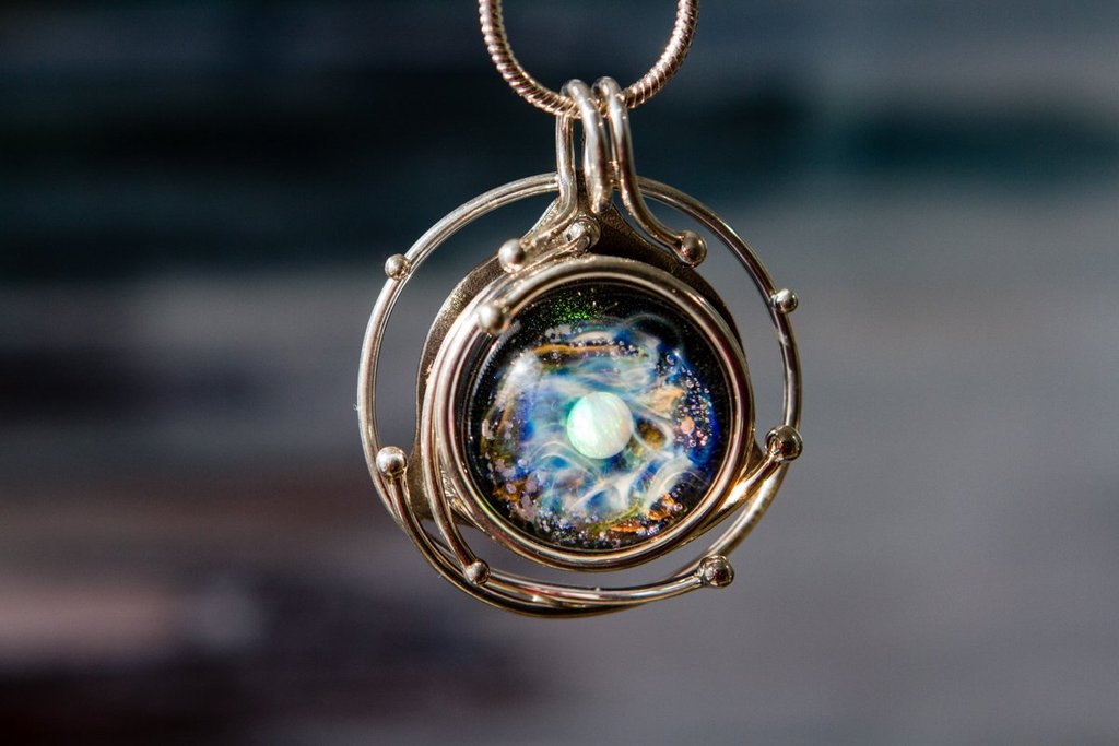 Circular wire wrapped pendant featuring a glass orb with blue and white swirls.