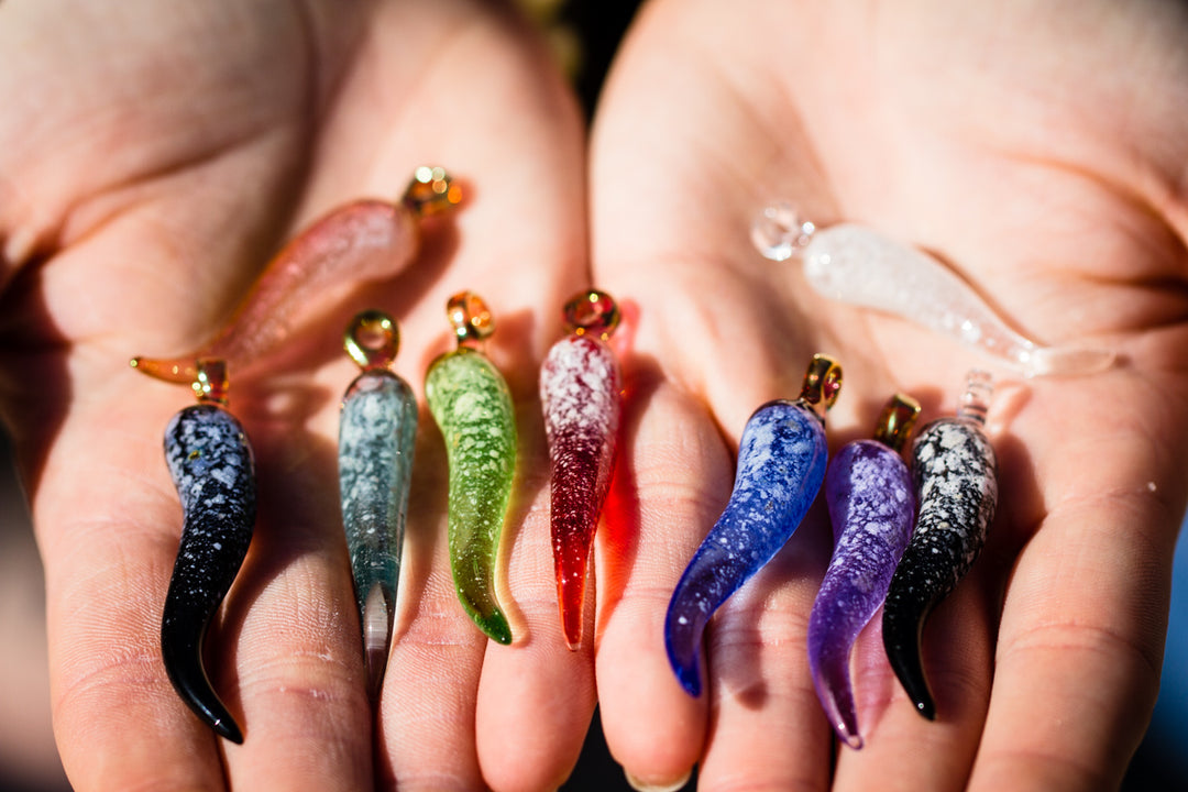 Assorted colorful cremation jewelry horn pendants held in a hand