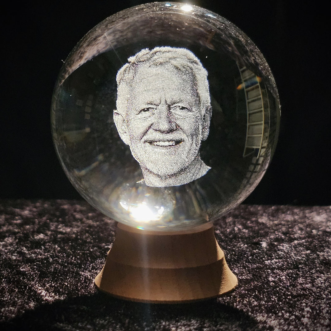 Crystal sphere with a detailed etched portrait of a smiling older man on a wood stand