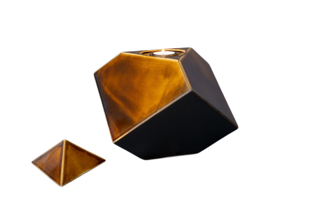 Abstract copper and black geometric ceramic urn with a built-in candle holder on top.