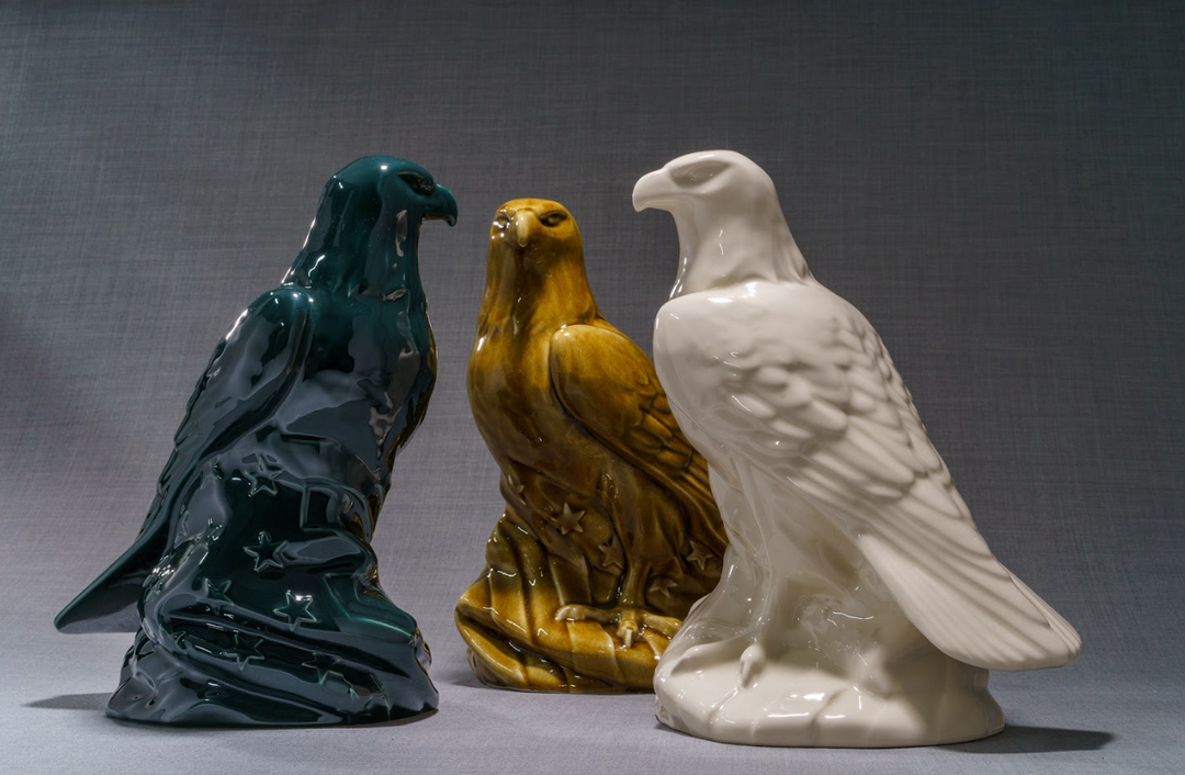 Three Aquilae ceramic urns in teal, amber, and white finishes arranged together.