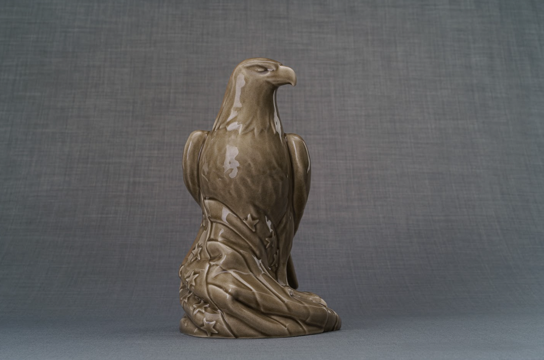 Brown ceramic urn shaped as a kneeling eagle with starry drapery at the base