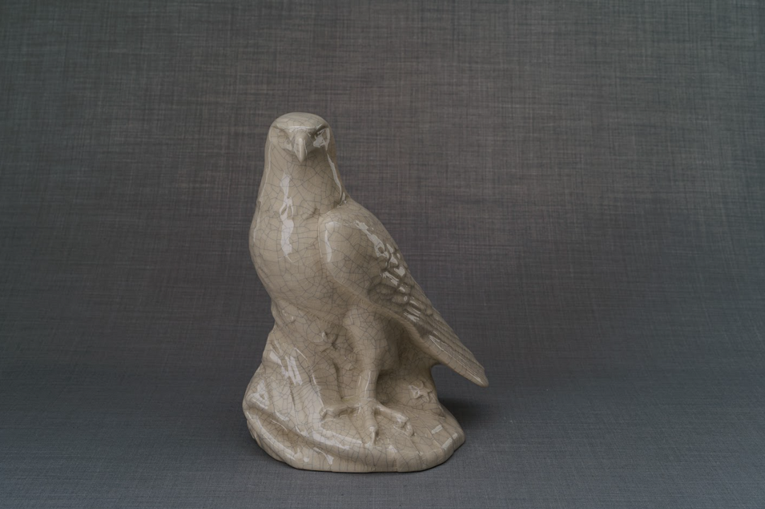 Beige crackle glazed urn with a standing eagle sculpture on a simple base
