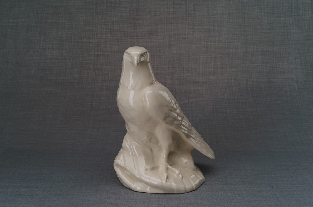Cream ceramic eagle sculpture perched on a rocky base outdoors