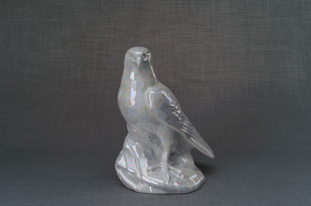 Aquilae iridescent white ceramic eagle urn perched on a rocky base