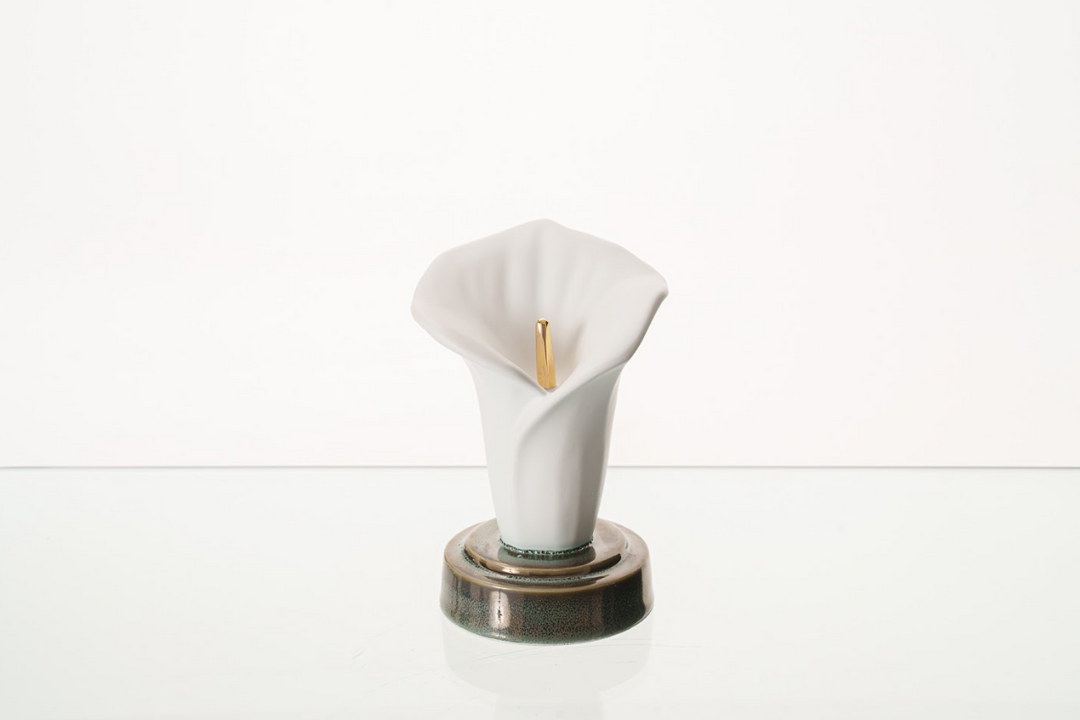 White ceramic calla lily urn with a gold center on a round glazed base.