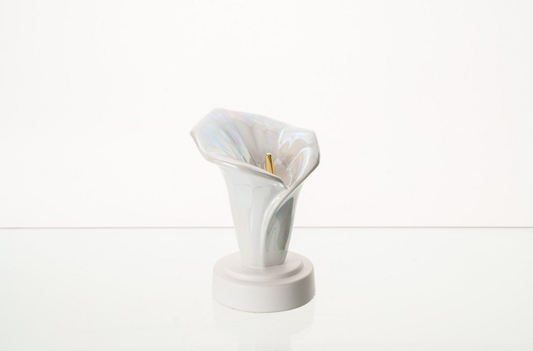 Iridescent white Calla Lily Keepsake Ceramic Urn on a white pedestal, bottom filled.