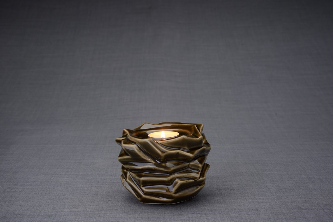 Brown sculpted ceramic urn with layered folds and a lit tealight at the top