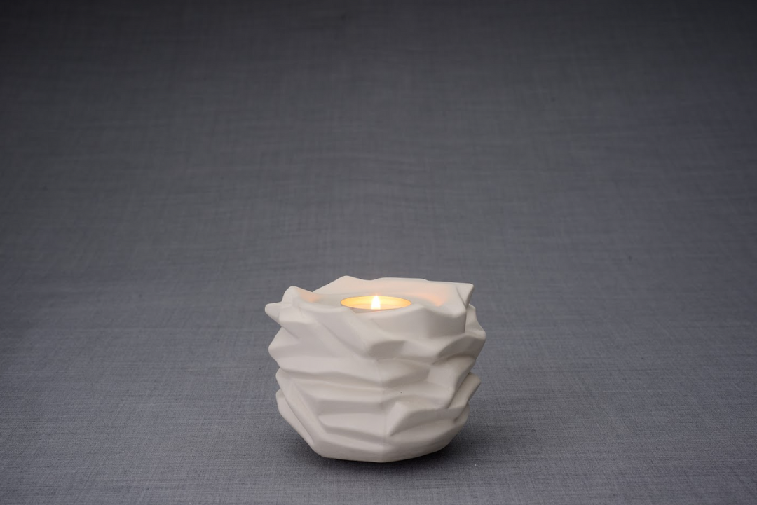White Christ Ceramic Urn sculpted as a candle holder with a lit tealight on top