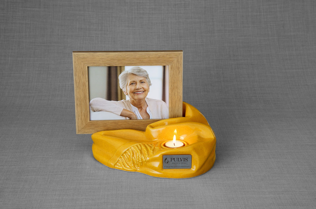 Yellow Cozy ceramic urn with a built in candle and a framed portrait of a smiling woman.