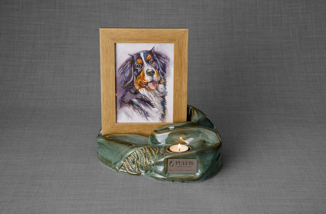Cozy green ceramic urn with built in wooden photo frame showing a dog's portrait and a candle
