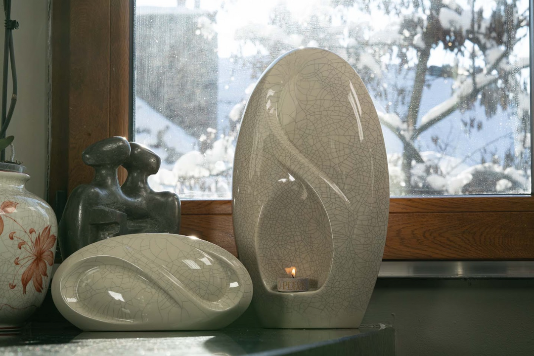 Eternity ceramic urn with candle holder shown among decorative ceramics on a windowsill.