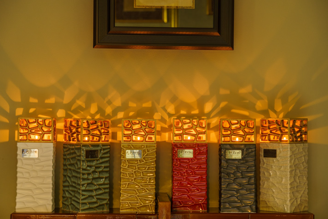 Six Everlasting Flame ceramic candle urns with warm amber glass tops lit to honor loved ones.