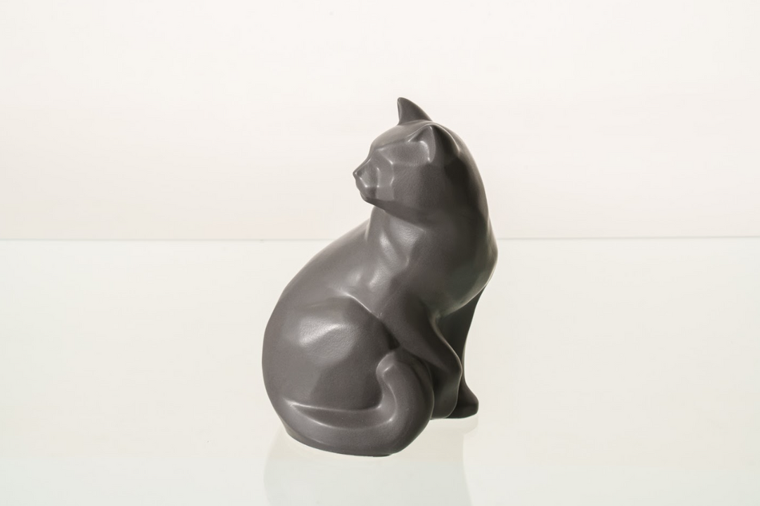 Felix cat urn in dark gray ceramic seated with tail curled beside its body.