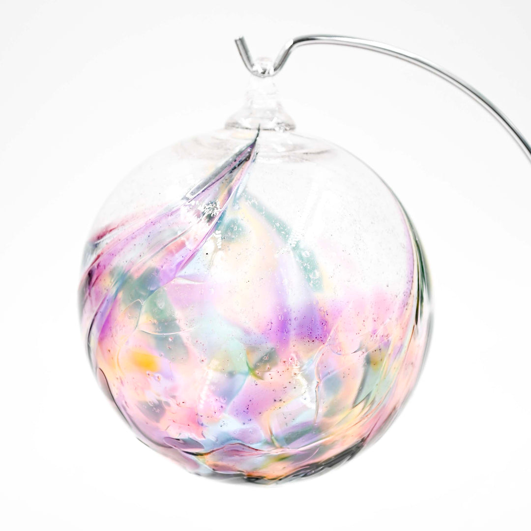 Clear glass ornament with pastel feathered patterns and a visible ash ribbon around the exterior with a curved metal hook