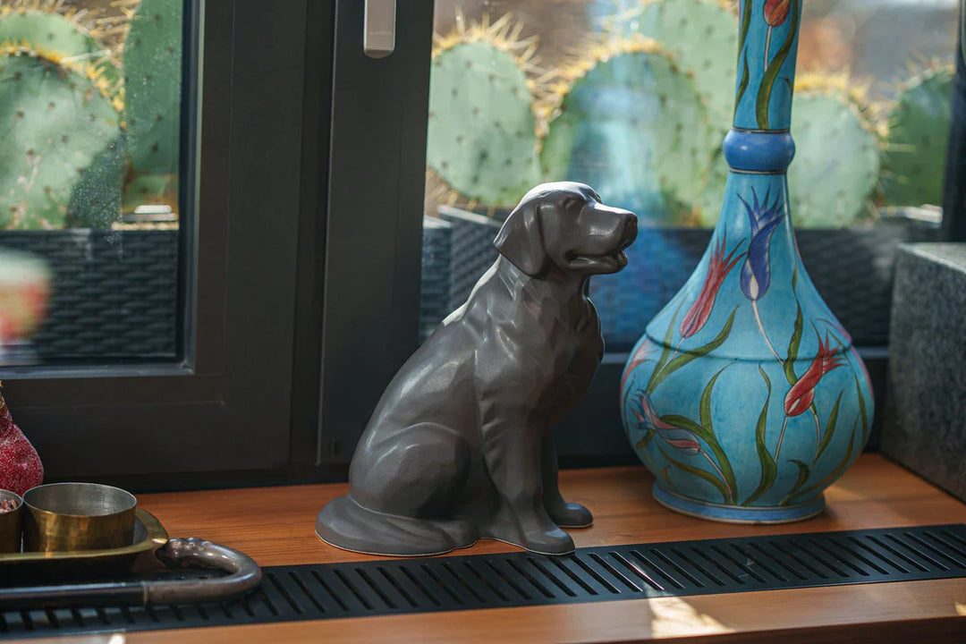 Gray ceramic Golden Retriever statue on a wooden shelf beside a blue floral vase