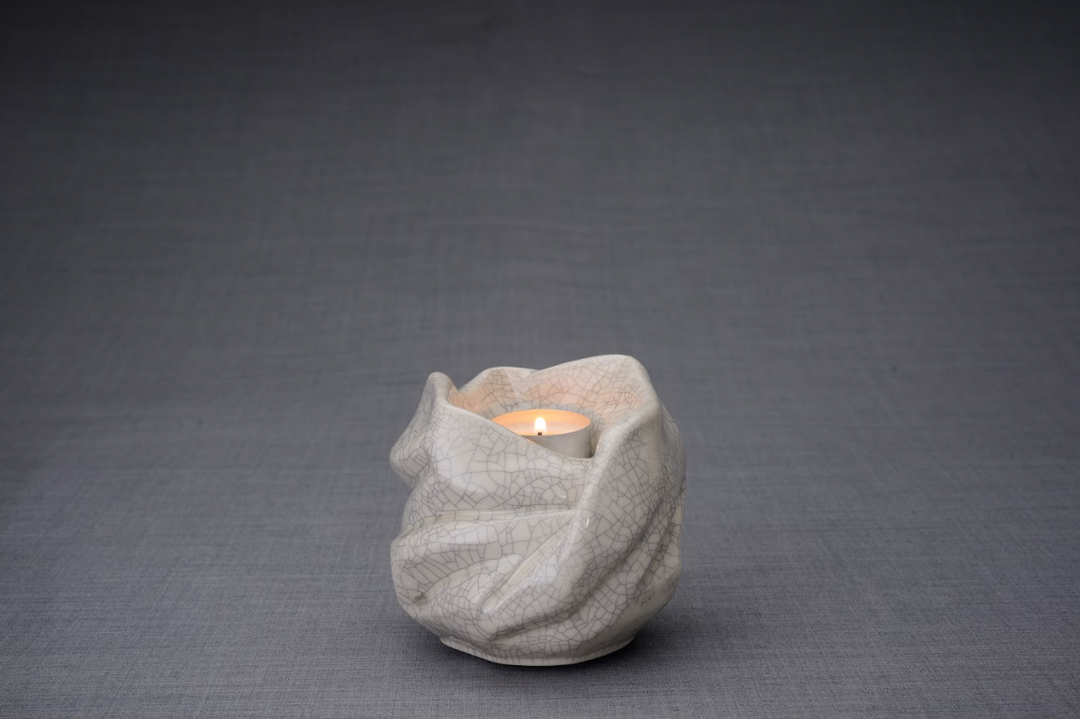 The Holy Mother white crackle glaze ceramic urn with flowing folds and a lit tealight candle.