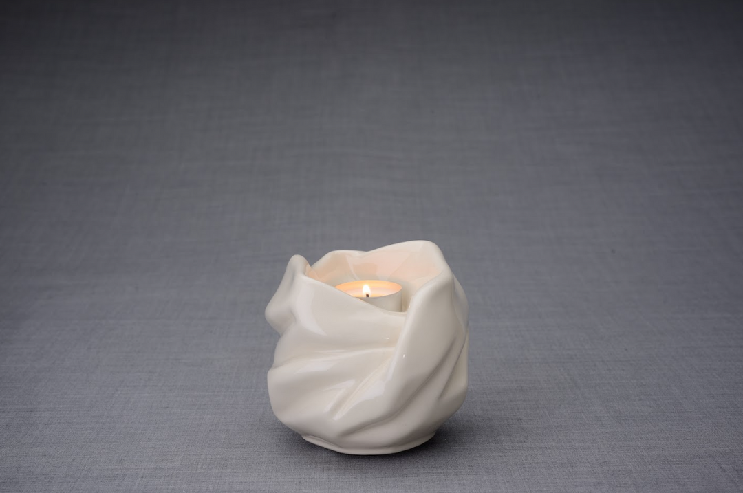 White glazed Holy Mother ceramic urn with a lit candle in the opening