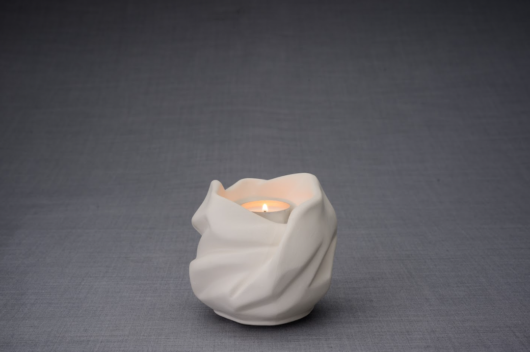 White Holy Mother ceramic urn with folded fabric like wrap and a lit candle inside