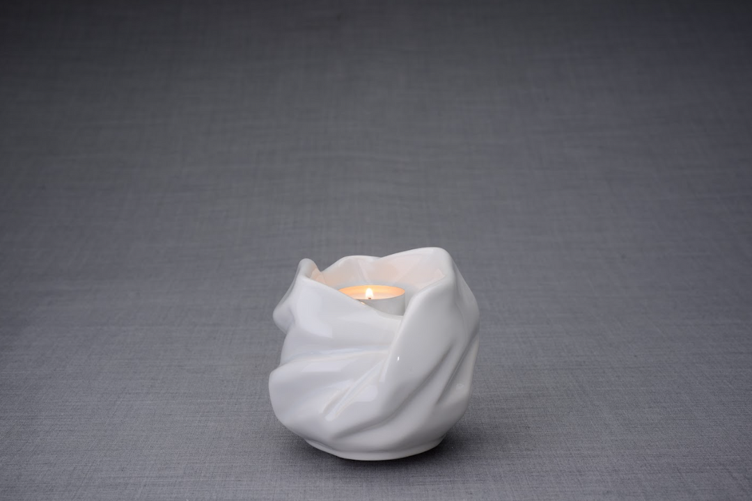 White Holy Mother urn with sculpted draped folds surrounding a softly lit candle