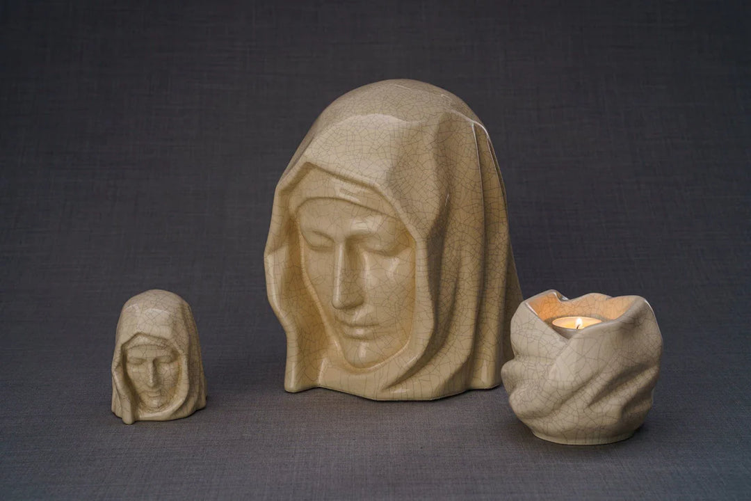 Beige Holy Mother sculpture with a candle holder and a smaller bust beside it on a textured gray surface