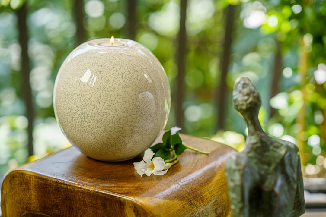 Harmony Ceramic Urn round mustard glaze with built in candle holder and a lit tea light on wood.