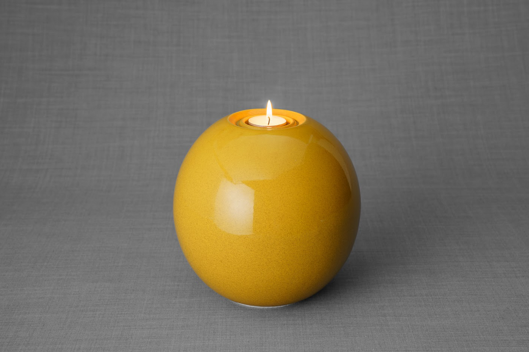 Harmony Ceramic Urn amber glaze spherical form with a built in candle holder and flame.
