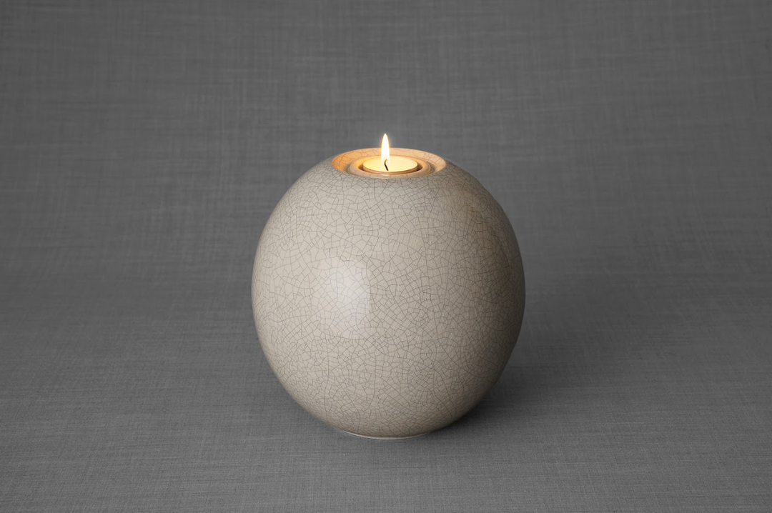 Harmony ceramic urn in gray crackle glaze with built in candle holder and a lit candle.