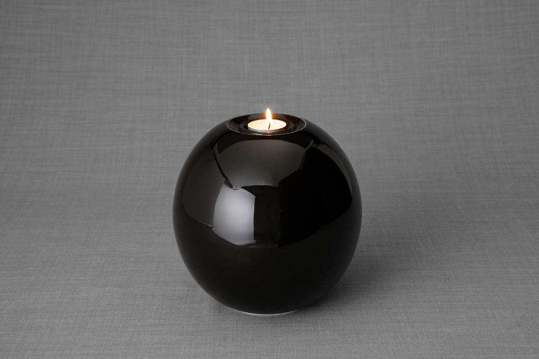 Harmony ceramic urn in glossy black glaze with candle on top.