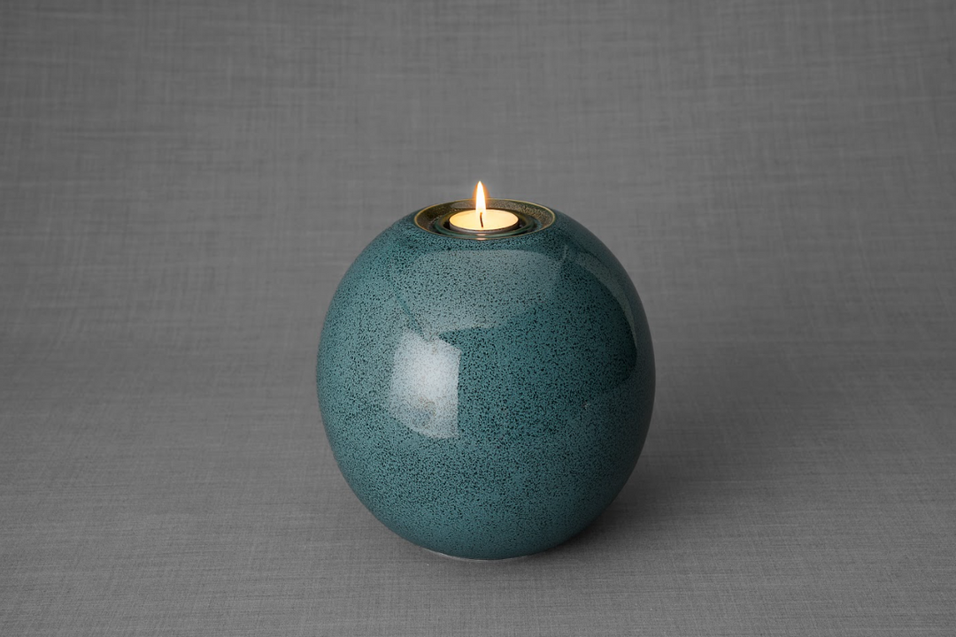 Teal round Harmony ceramic urn with candle holder on top against a gray studio backdrop.