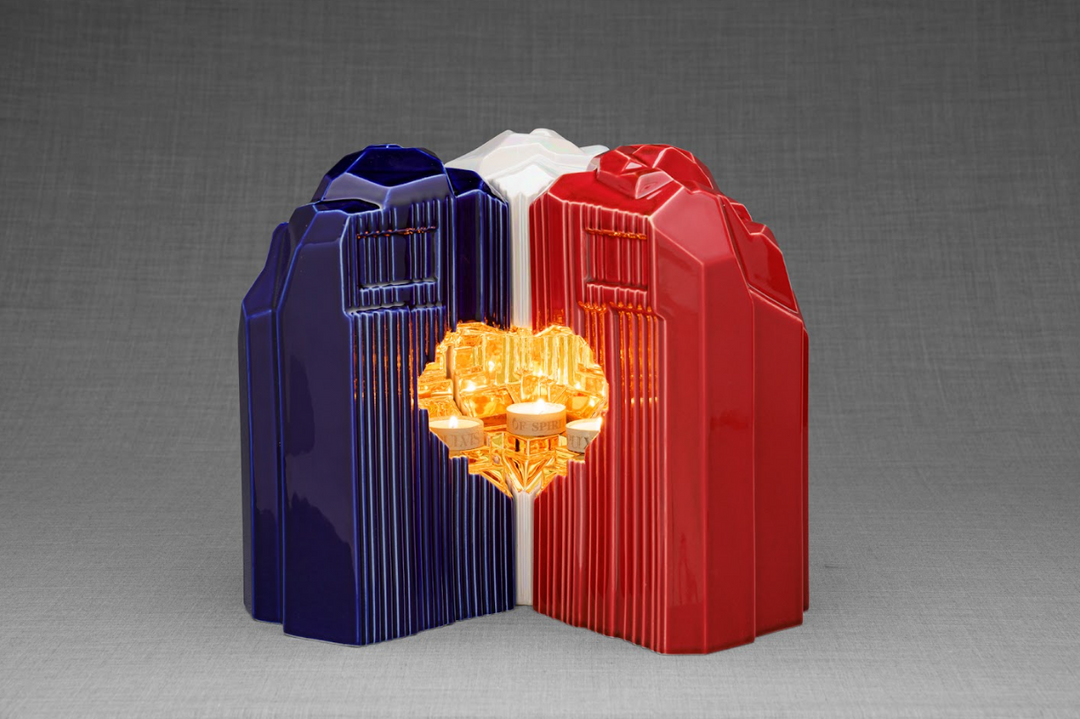 Heart shaped ceramic urn with blue and red panels and a glowing candle inside the hollow center