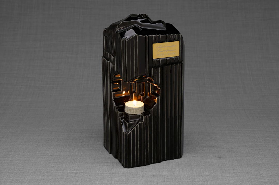 Black Heart Ceramic Urn with gold plaque and lit candle inside the heart opening