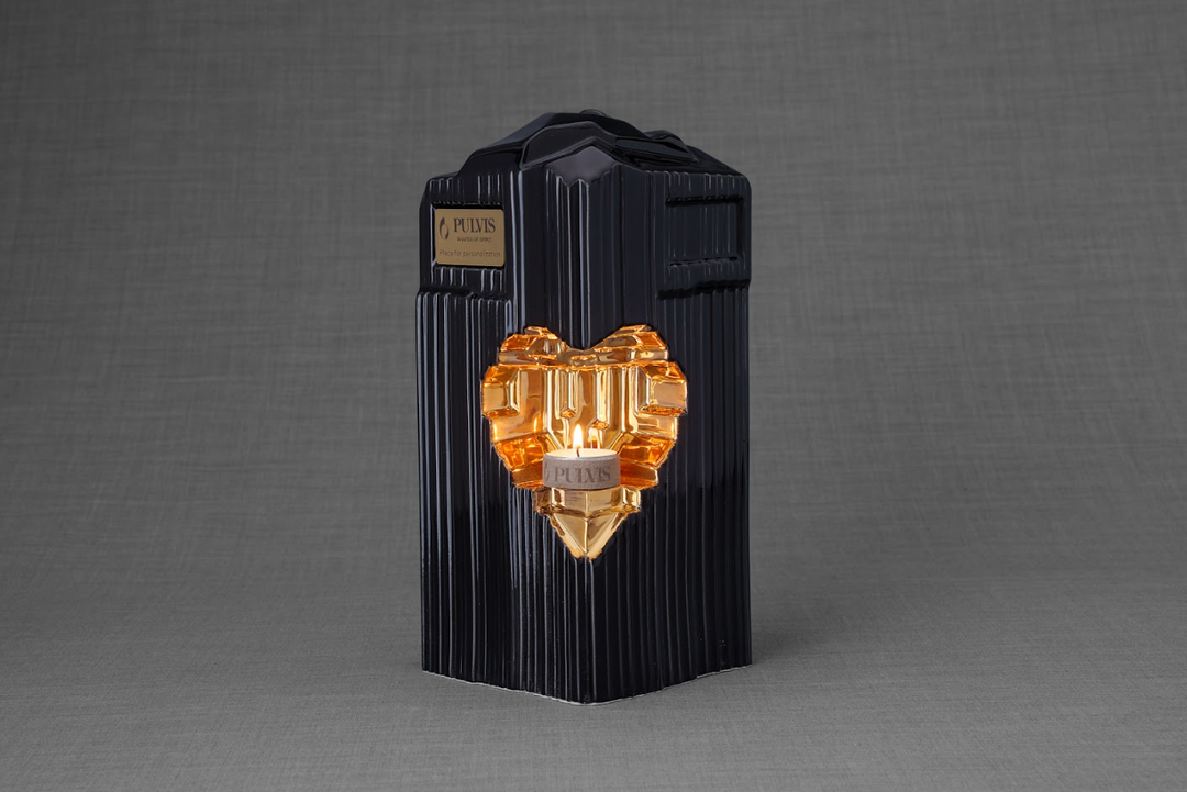 Black Heart Ceramic Urn with ornate gold heart inset and a lit candle at the center