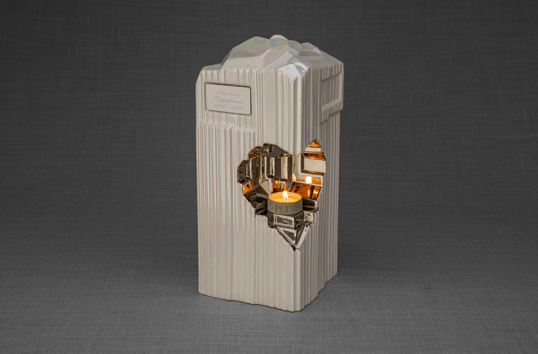 Cream ribbed Heart ceramic urn with a gold heart insert and a lit candle in the heart opening.