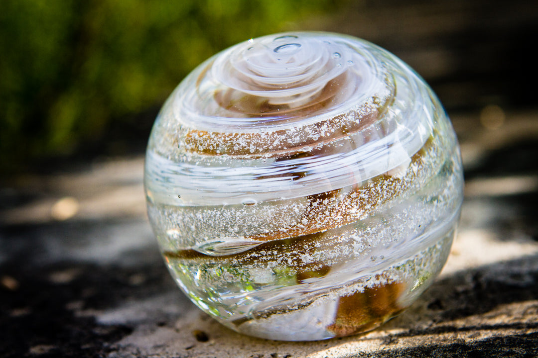 Golden Sparkle Orb with white swirls and speckles resting outdoors