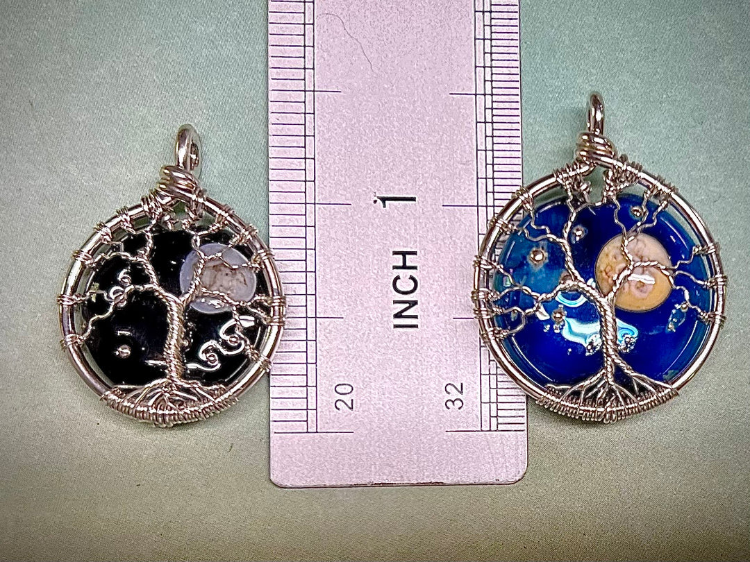 Two circular pendants with intricate designs on a ruler for scale.