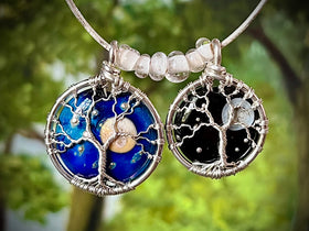 Two tree-themed pendants on a blurred green background
