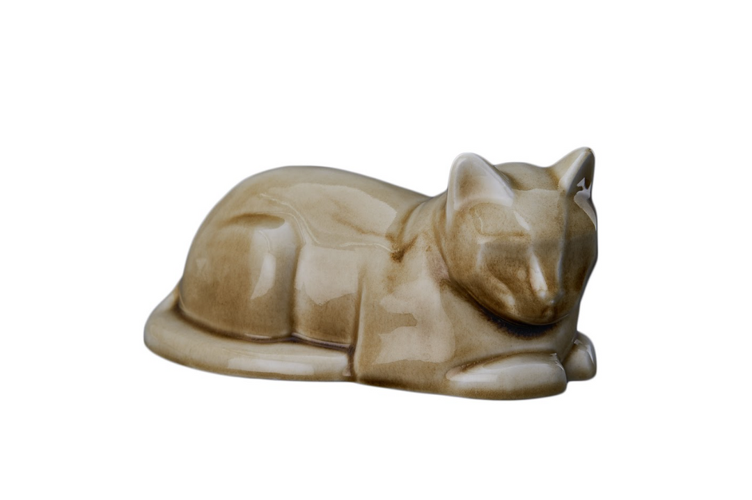 Beige glazed ceramic laying cat urn resting on a surface