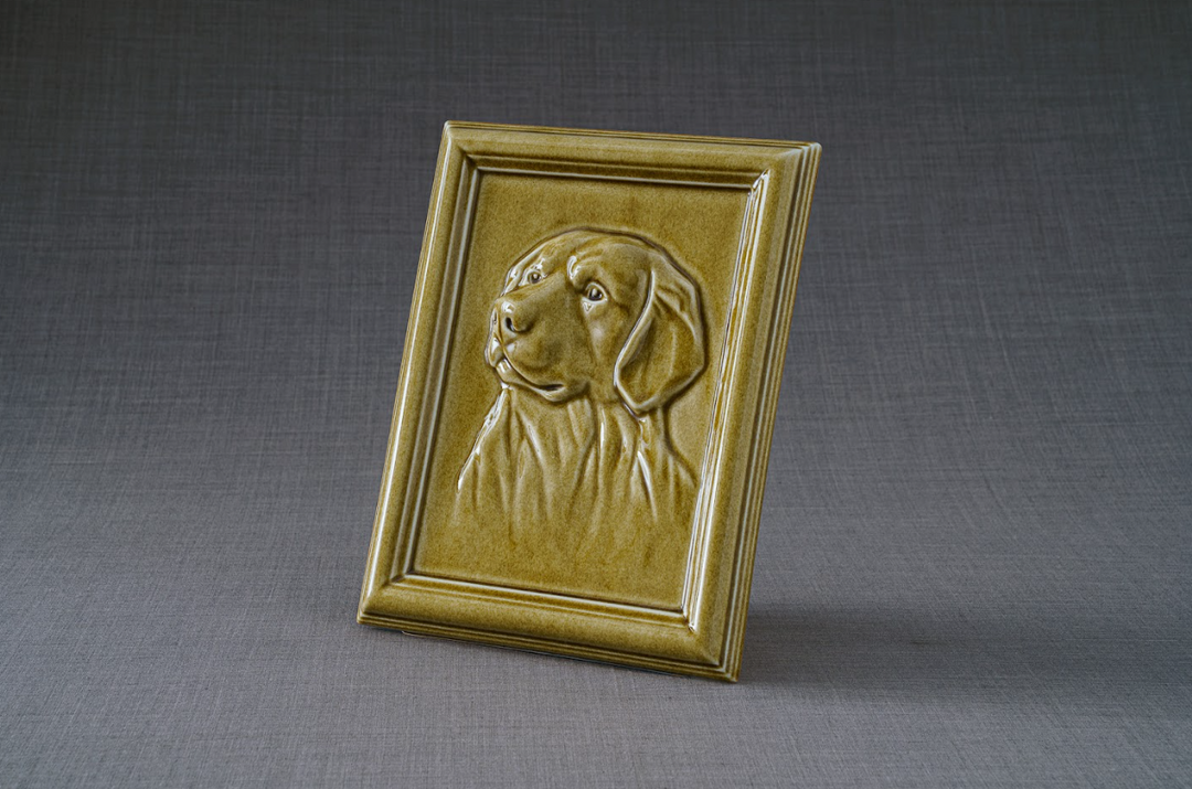 Gold Labrador Frame Ceramic Urn with embossed dog portrait in a warm gold frame against a gray backdrop.