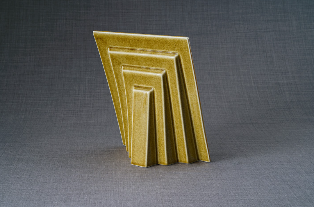 Golden Labrador frame ceramic urn with nested rectangular panels leaning on a gray backdrop.